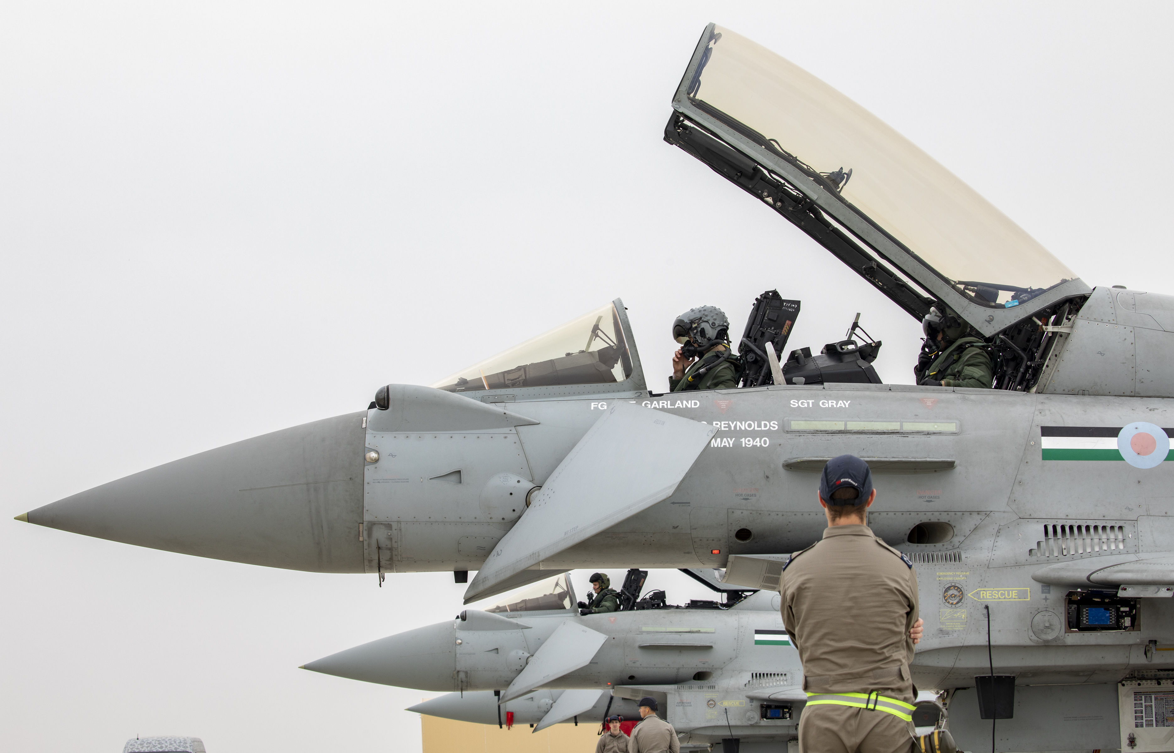 Image shows personnel in the cockpit of a fighter jet on the airfield.